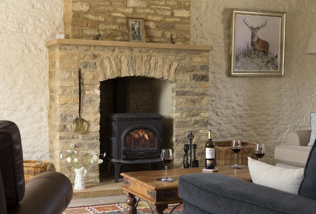 a living room with a stone fireplace with wine glasses at Alysas Cottage in Chipping Norton