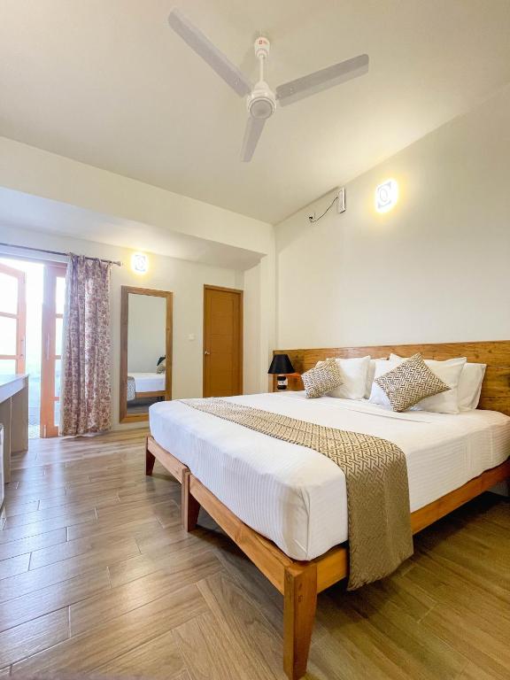 a bedroom with a large bed with a ceiling fan at Suffix Retreat - Stay, Dive & Explore Fuvahmulah in Fuvahmulah
