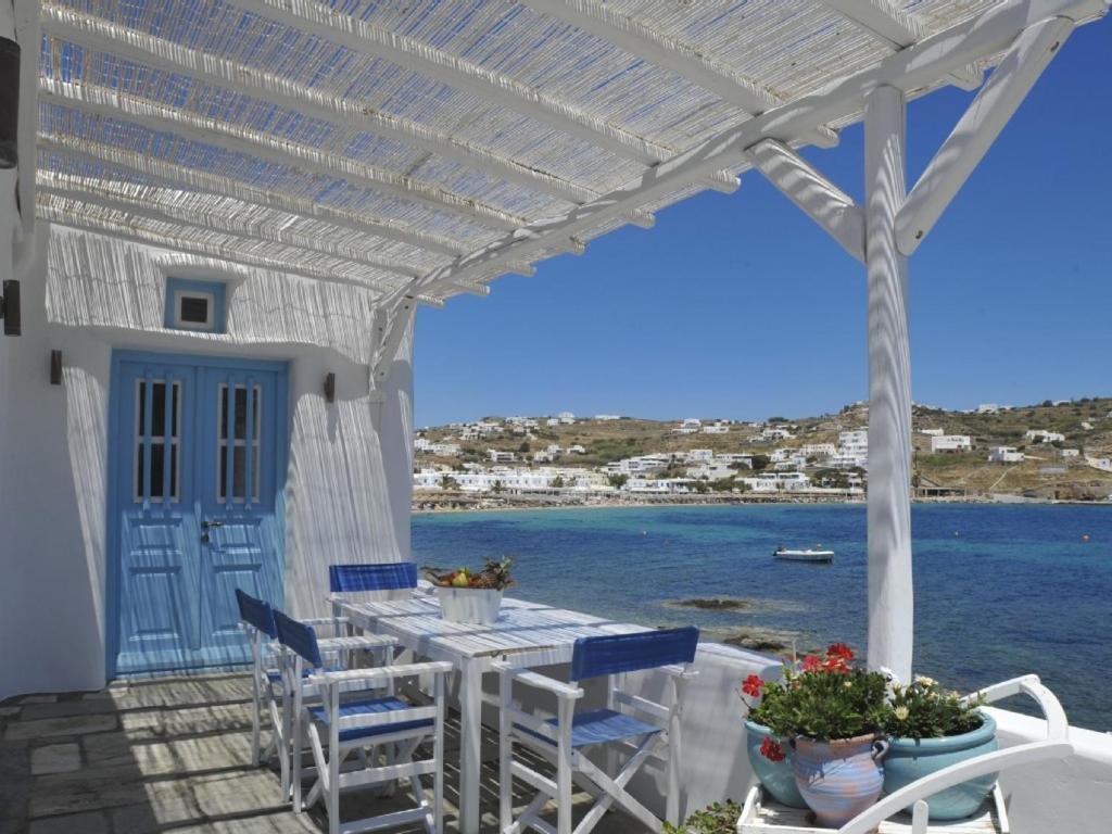 a patio with a table and chairs and the ocean at Luxury Sea House By Blue Waters Mykonos in Ornos