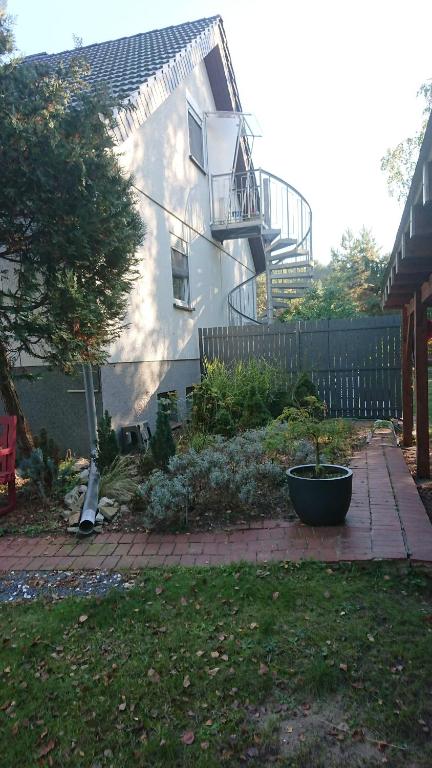 ein Haus mit einem Balkon und einem Hof mit einer Pflanze in der Unterkunft Klimatisiertes Ferienapartment an der Stadtgrenze von Berlin in Gosen