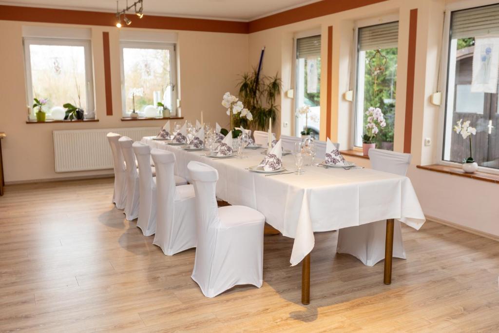 a long white table and chairs in a room at Pension Zum Lindeneck in Lübz