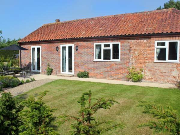a red brick house with a yard with a lawn sidx sidx sidx at Moat Farm Cottage in Wood Dalling