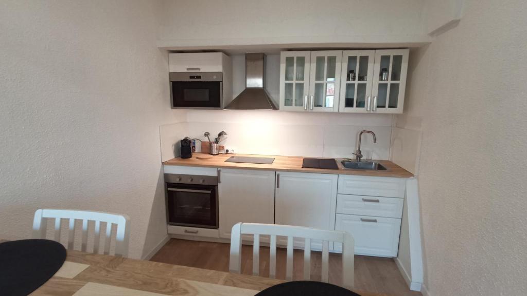 a small kitchen with white cabinets and a table and chairs at Studio Neuf Climatisé Centre Ville #7 in Toulon