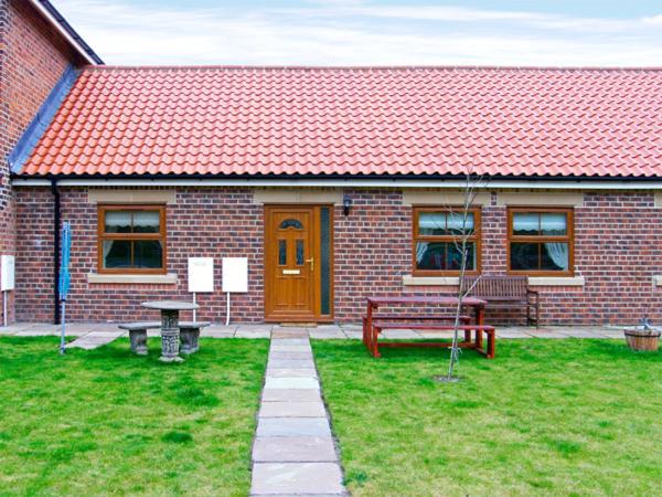 a brick house with a bench and a table in the yard at Drummer Cottage in Loftus