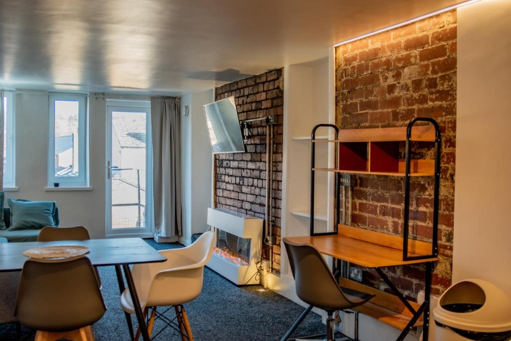 a room with a table and chairs and a brick wall at BvApartments Dealhouse Nine in Huddersfield