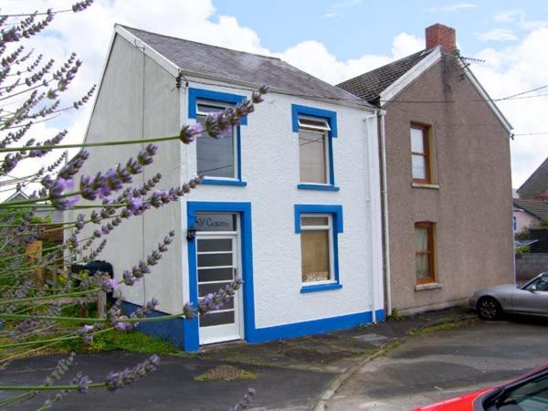 a blue and white house with a car parked in front of it at Y Garth in Ferryside