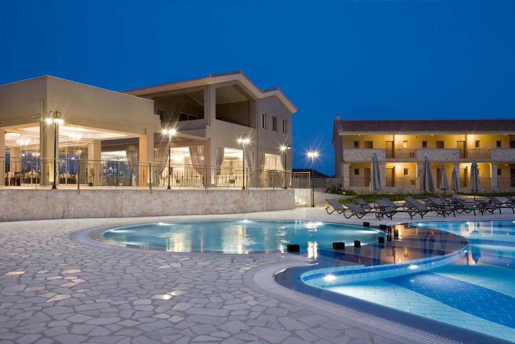 a swimming pool in front of a building at night at Magnolia Resort in Katelios