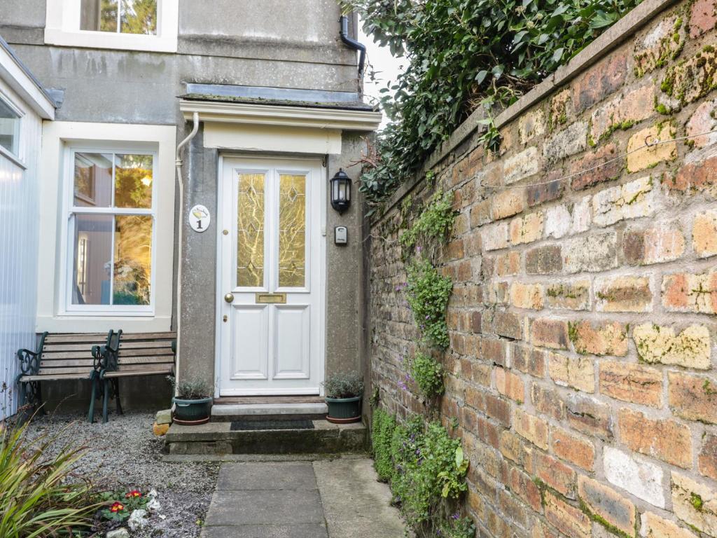 a white door on a brick wall with a bench at 1 Rubby Banks Road in Cockermouth