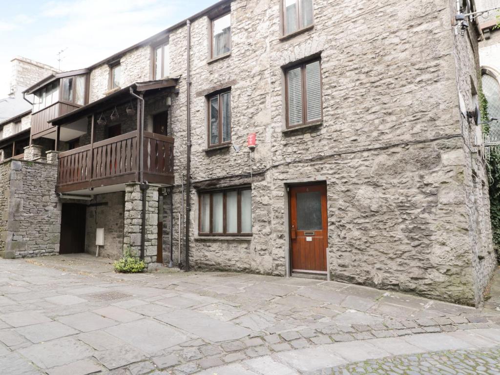 a stone building with a balcony and a wooden door at 11 Camden Building in Kendal