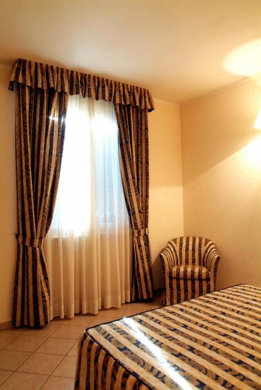 sypialnia z łóżkiem i oknem z zasłonami w obiekcie Hotel La Maddalena w mieście Quattro Castella