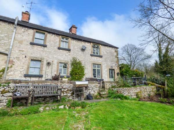 a stone house with a bench in front of it at River Cottage in Bakewell