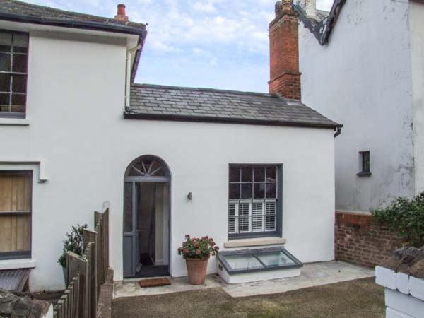 a white house with a door and a window at Woodland Cottage in Malvern Wells