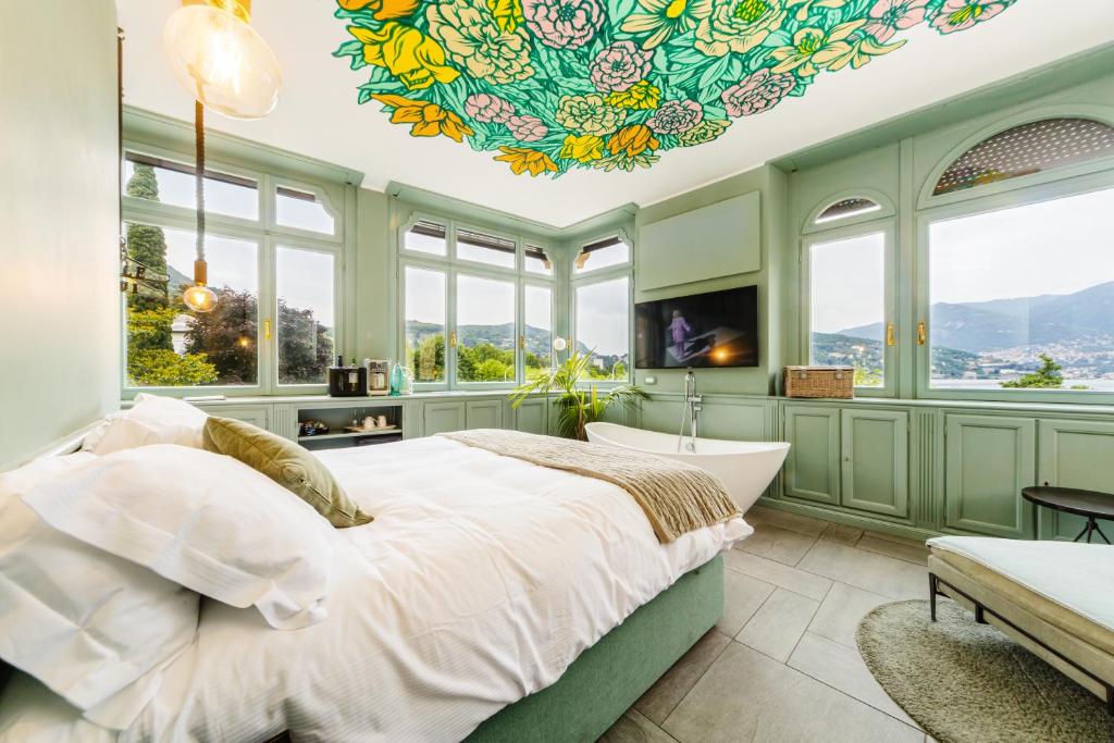 a bedroom with a large bed with a tub and windows at Bello!Lake Como Suites in Como