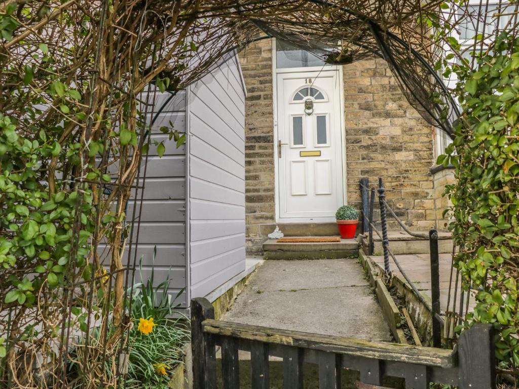 a white door on a brick house with a gate at Angel Cottage in Skipton
