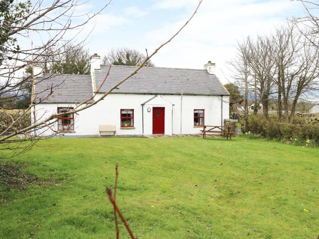 a white house with a red door in a yard at Callaghan's in Kilkeel