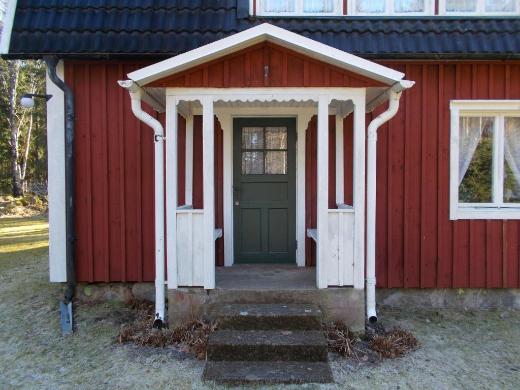 a red shed with a green door and stairs at Furulund in Linneryd