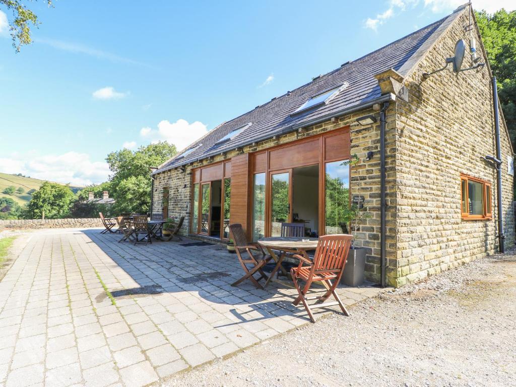 a brick building with a table and chairs on a patio at Hove Wood View in Hebden Bridge