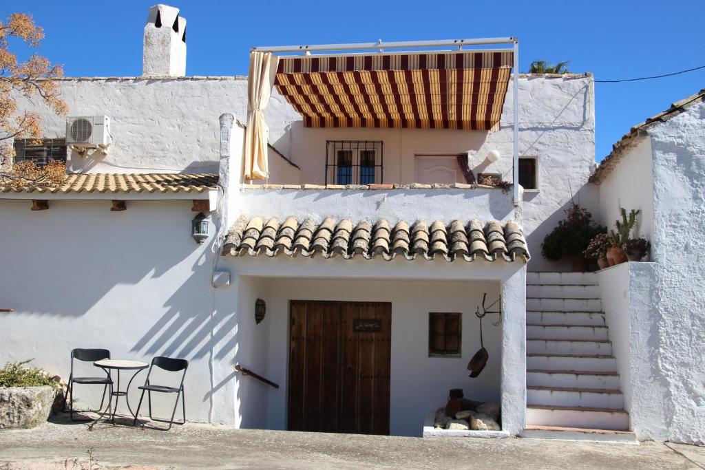 ein weißes Haus mit einem Tisch und Stühlen davor in der Unterkunft Appartement El Patio (cortijo La Cubertilla) in Fuente-Tójar