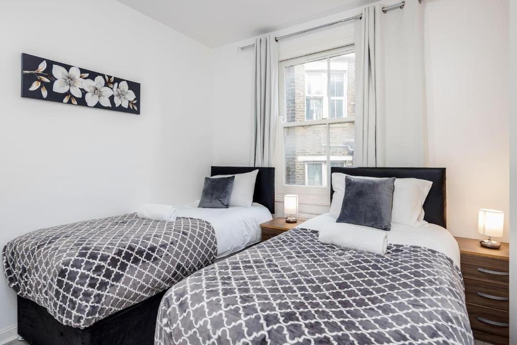2 letti posti uno accanto all'altro in una camera da letto di Stunning 1-Bed Apartment in London Lewisham a Londra