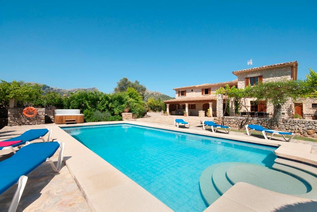 a swimming pool with chairs and a house at Villa Cal Apostol in Pollença