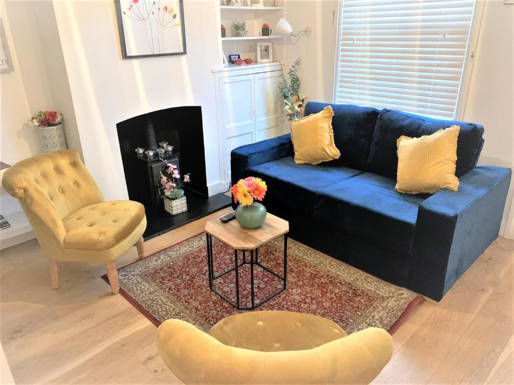 uma sala de estar com um sofá azul e uma cadeira em Riverside Channel5 "Holidays Homes in the Sun" Featured Central Canterbury Cottage with Free Parking em Canterbury