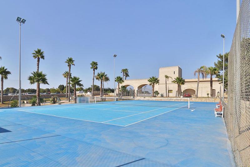 a tennis court in front of a building with palm trees at HOTEL BARONE DI MARE in Torre dell'Orso