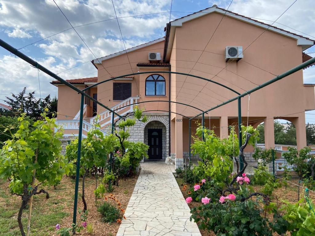 uma grande casa cor-de-rosa com um caminho à sua frente em Apartman Ivanka em Barbat na Rabu