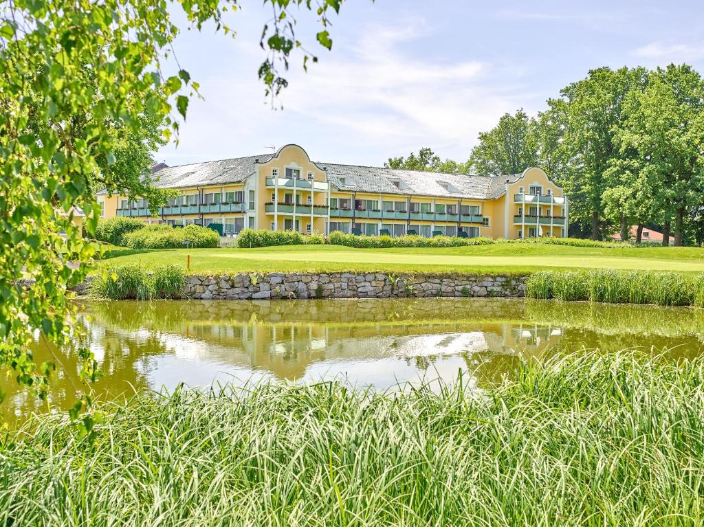 a view of the hotel from across a pond at Gutshof Penning in Rotthalmünster