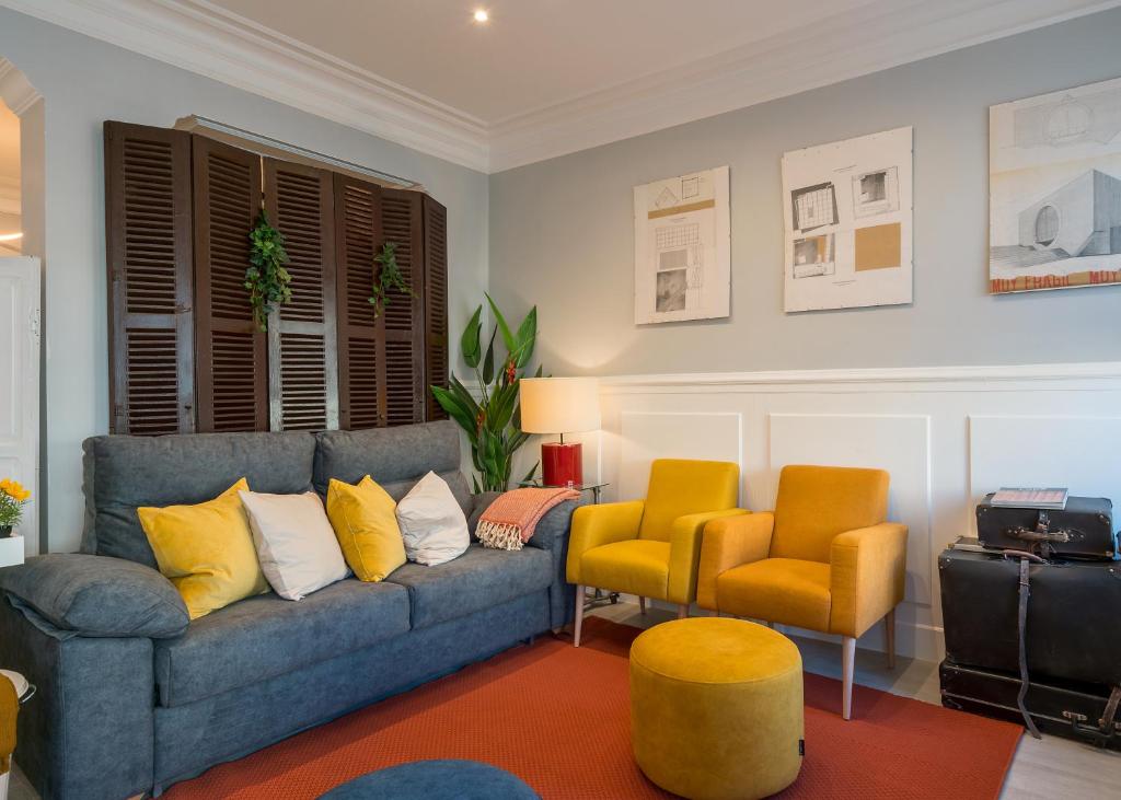 uma sala de estar com um sofá azul e duas cadeiras amarelas em L' ATELIER DEL ARRIAGa em Bilbao