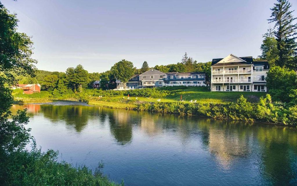 a large house sitting on the side of a river at The Shire Woodstock in Woodstock