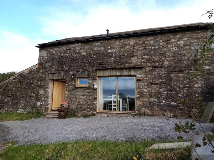 a stone building with a window on the side of it at Rural getaway with a view - Old Spout Barn in Sedbergh