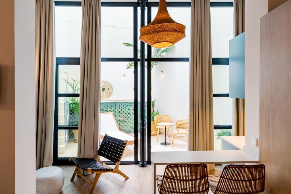 a living room with large windows and a table and chairs at Casa Bailen Sevilla in Seville