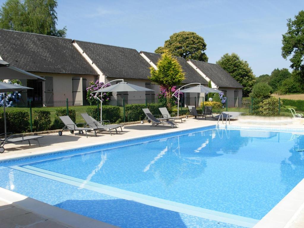 a swimming pool with chairs and a house at Hôtel Restaurant Les Coquelicots, The Originals Relais (Inter-Hotel) in Saint-Pardoux-lʼOrtigier