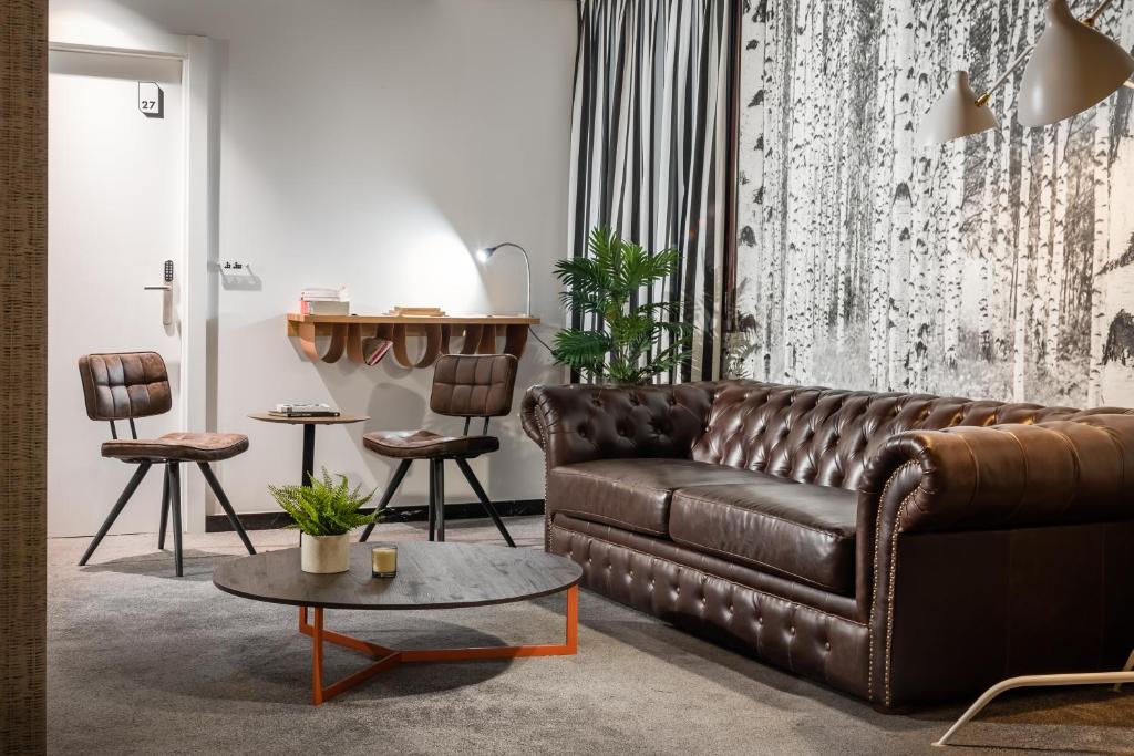 a living room with a brown leather couch and a table at BYPILLOW Amari in Bilbao