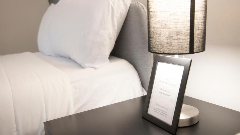 a lamp on a table next to a bed at Hotel Singular Antara in Mexico City