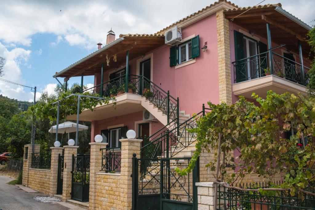 une maison rose avec un balcon dans l'établissement Anna's Apartments, à Nikiana