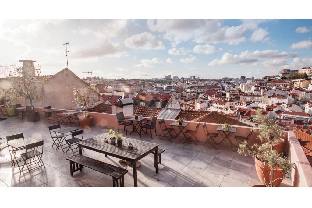 a balcony with tables and chairs and a view of a city at This Is Lisbon Hostel in Lisbon