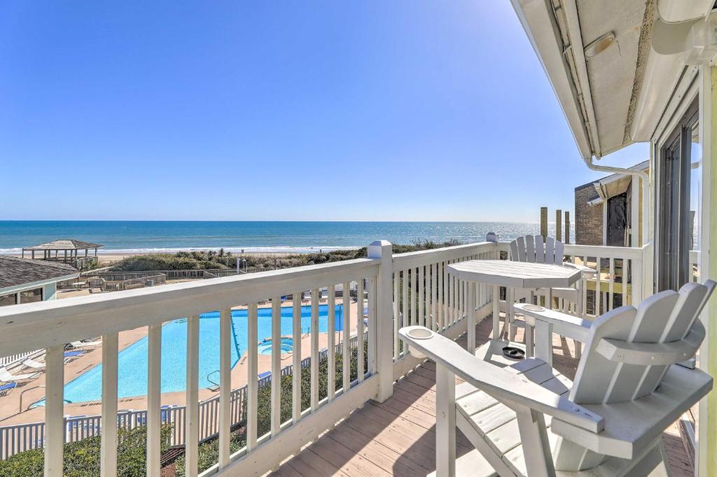 a balcony with a table and chairs and the beach at Coastal Condo with Indoor and Outdoor Pool Access in Emerald Isle