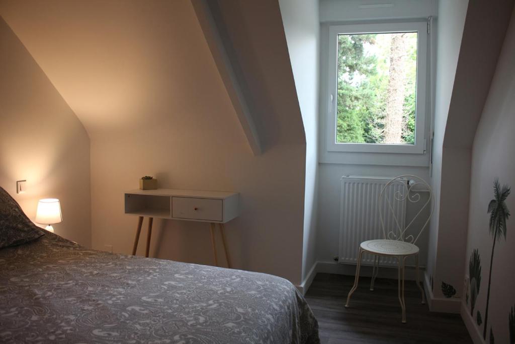 ein Schlafzimmer mit einem Bett, einem Fenster und einem Stuhl in der Unterkunft Ty Daou - Gîtes du Vieux Tilleul in Tréglamus