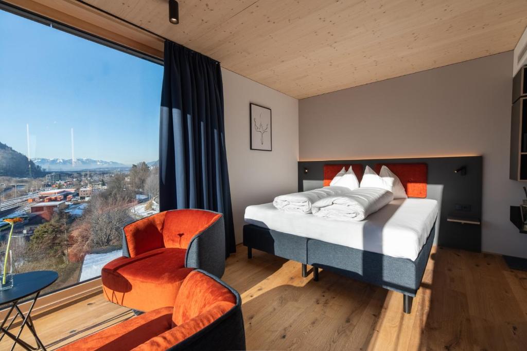 a bedroom with a bed and a large window at ALPSTADT LIFESTYLE Hotel in Bludenz