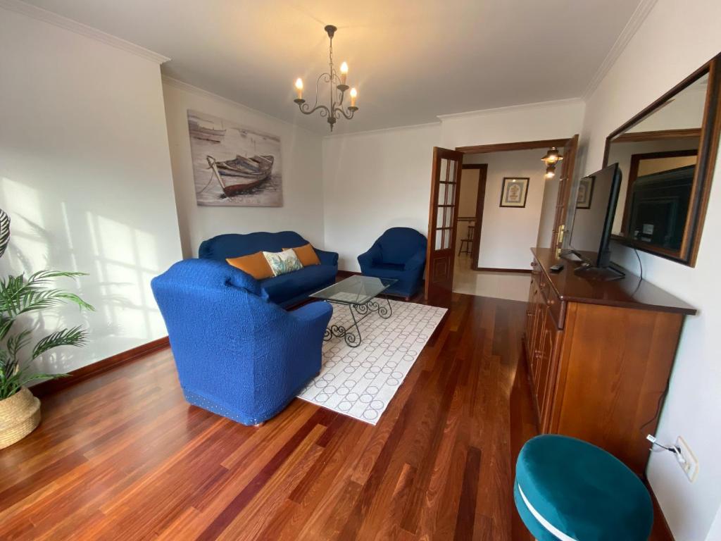 a living room with blue chairs and a television at Piso Os Pazos in Cambados