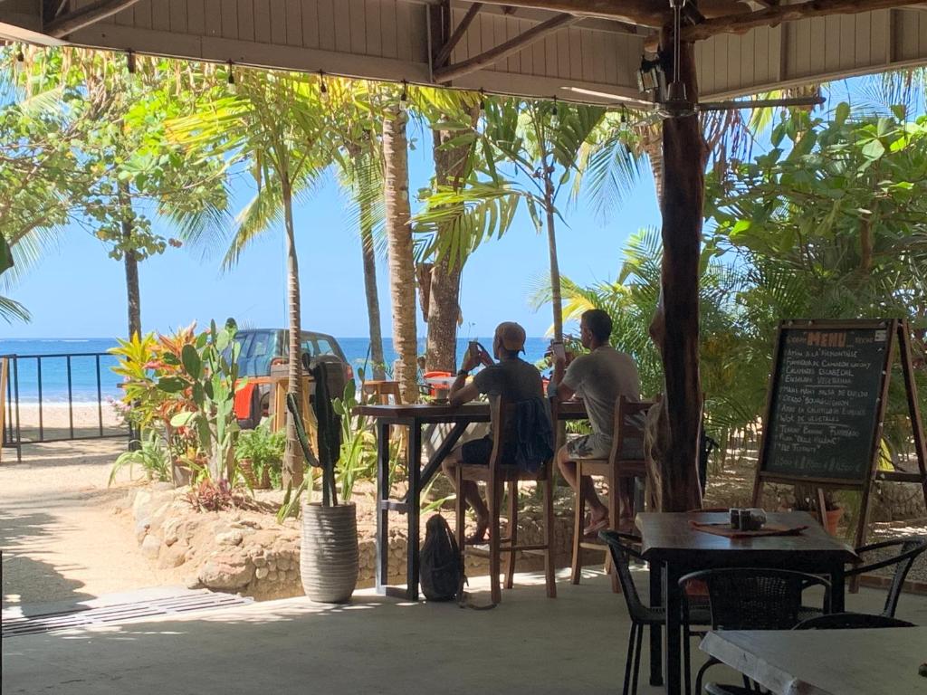 two people sitting at a table looking at the ocean at Beach Front Bahia in Sámara