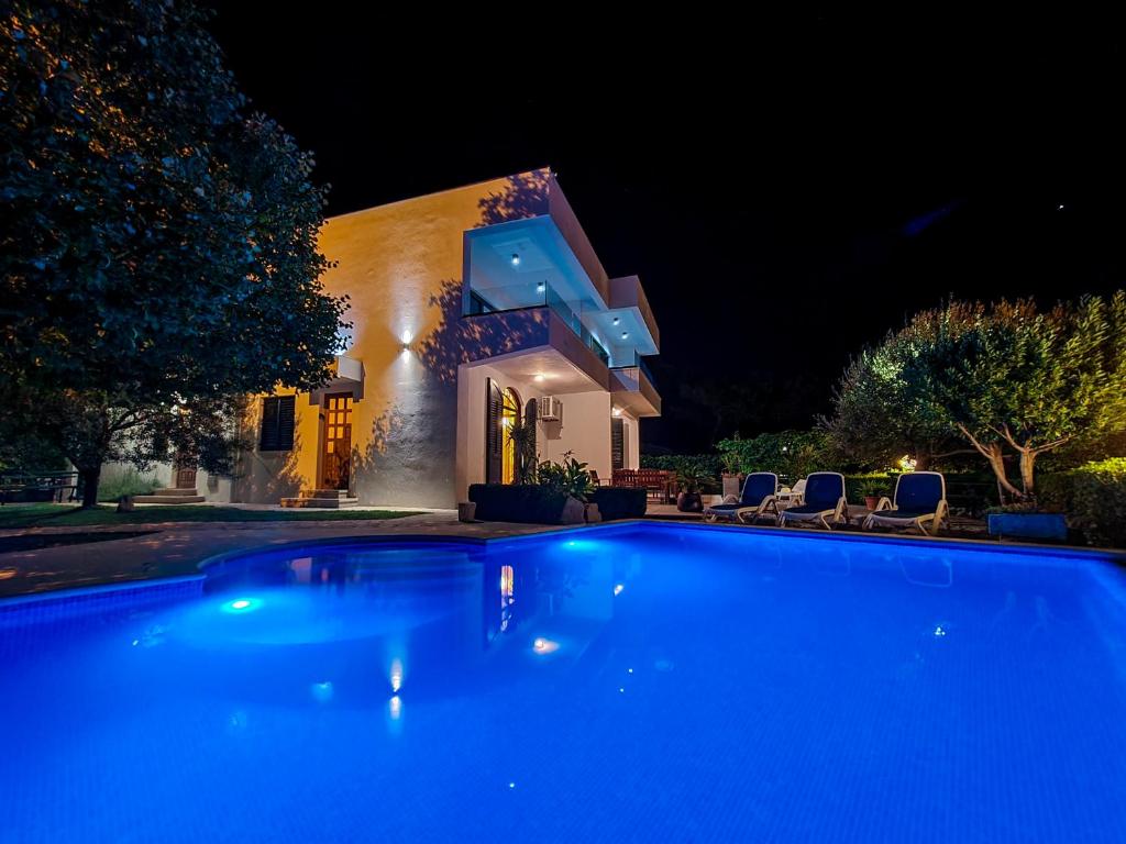 a swimming pool in front of a house at night at Apartments Lovic in Lokva Rogoznica