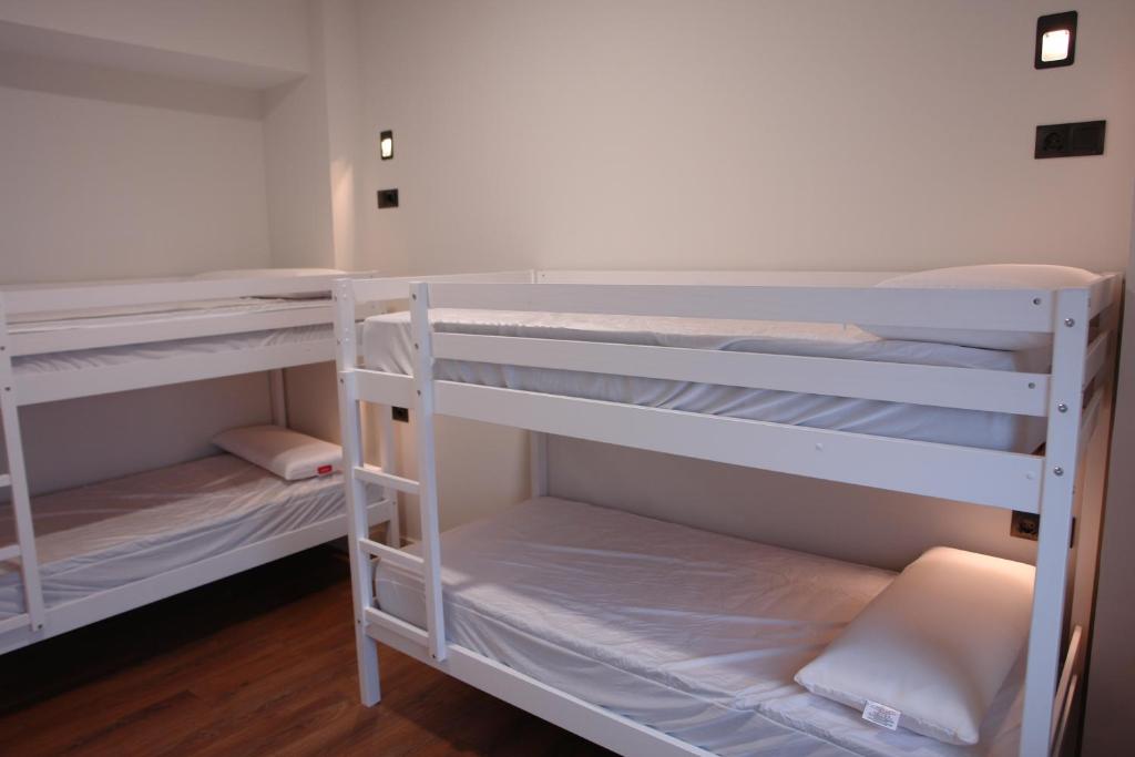 Pokój z 2 łóżkami piętrowymi i białymi półkami w obiekcie Hostel Trovadores w mieście Burgos