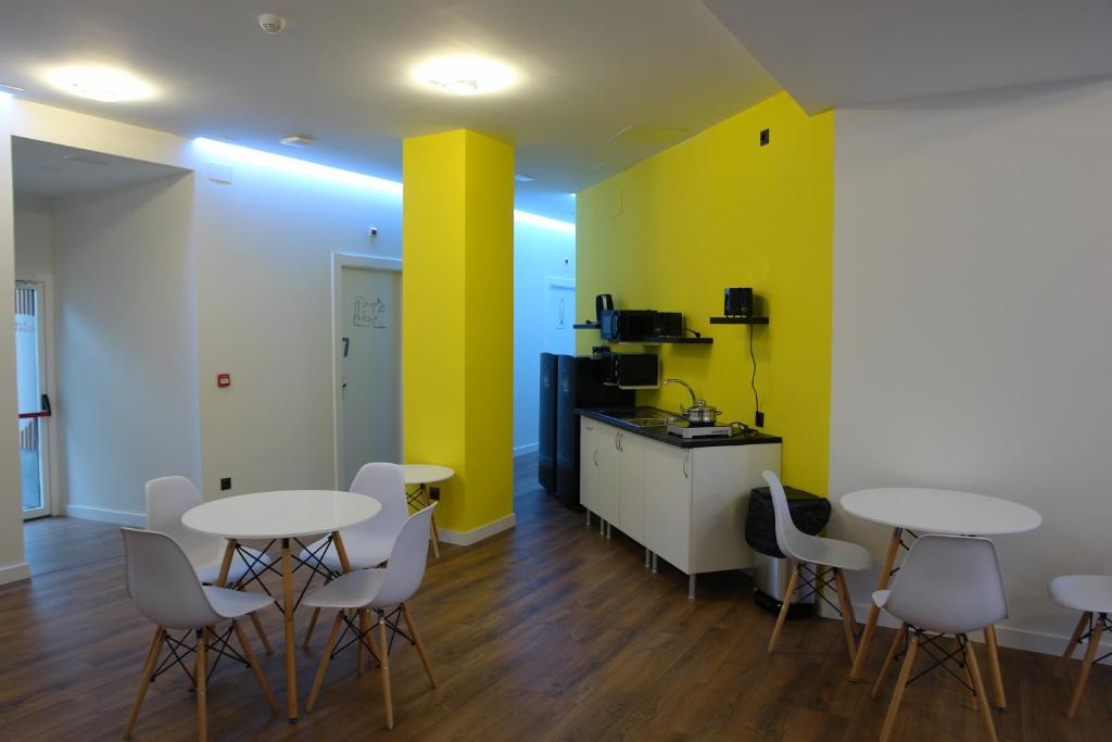Pokój z 2 stołami i krzesłami oraz kuchnią w obiekcie Hostel Trovadores w mieście Burgos
