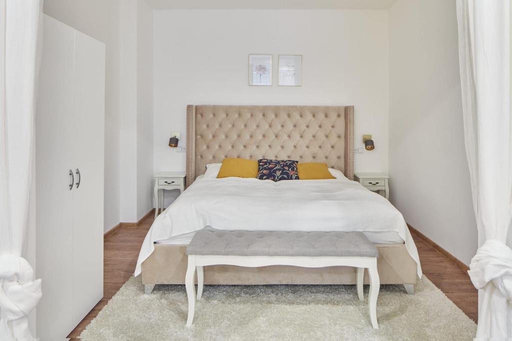 a white bedroom with a large bed with a large headboard at Helen Homestay Žižkov in Prague