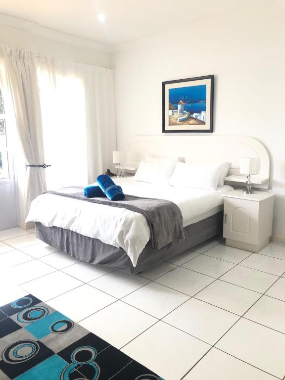 a white bedroom with a large bed and a window at Caribbean Estates Villa 26 Calypso Drive in Port Edward