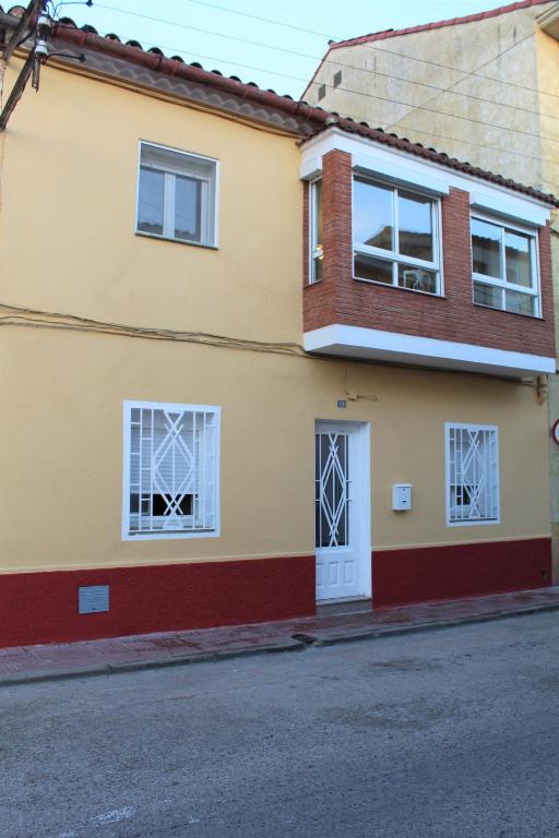 a yellow house with white windows and a street at Casa Victor in Benissanet