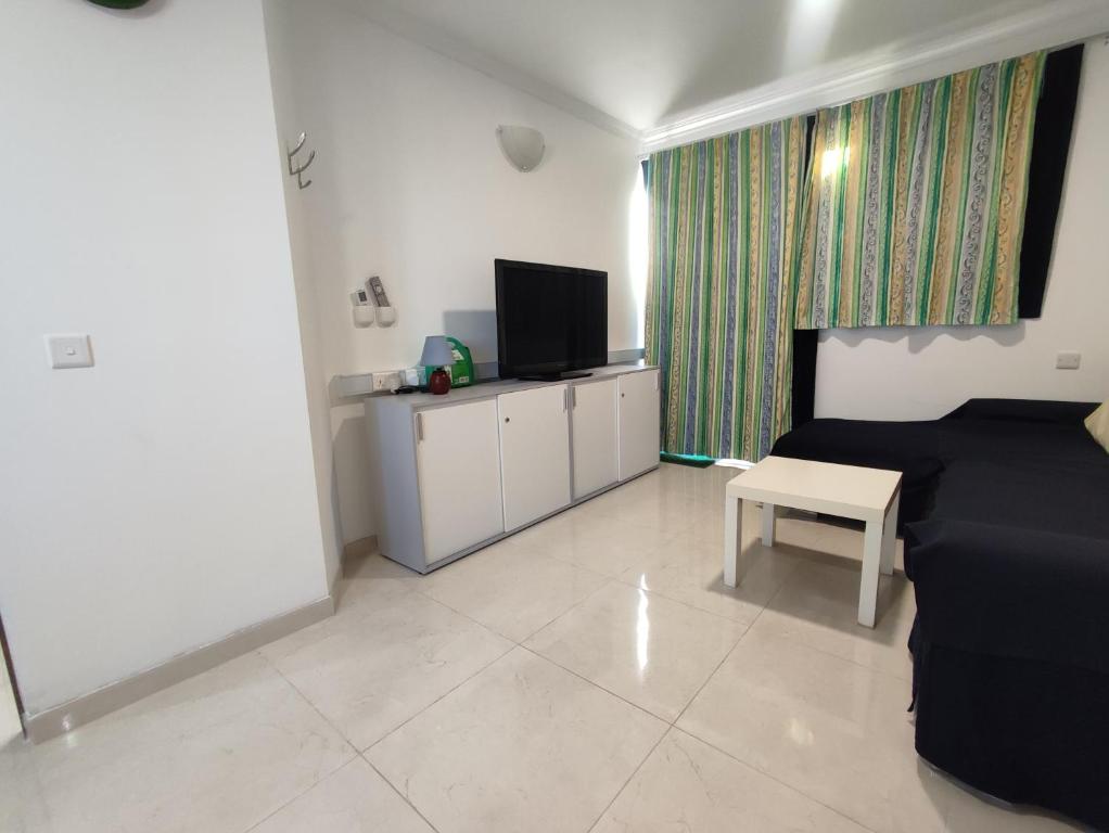 a living room with a black couch and a tv at One Bed Room Apartment with terrace in Marsaskala
