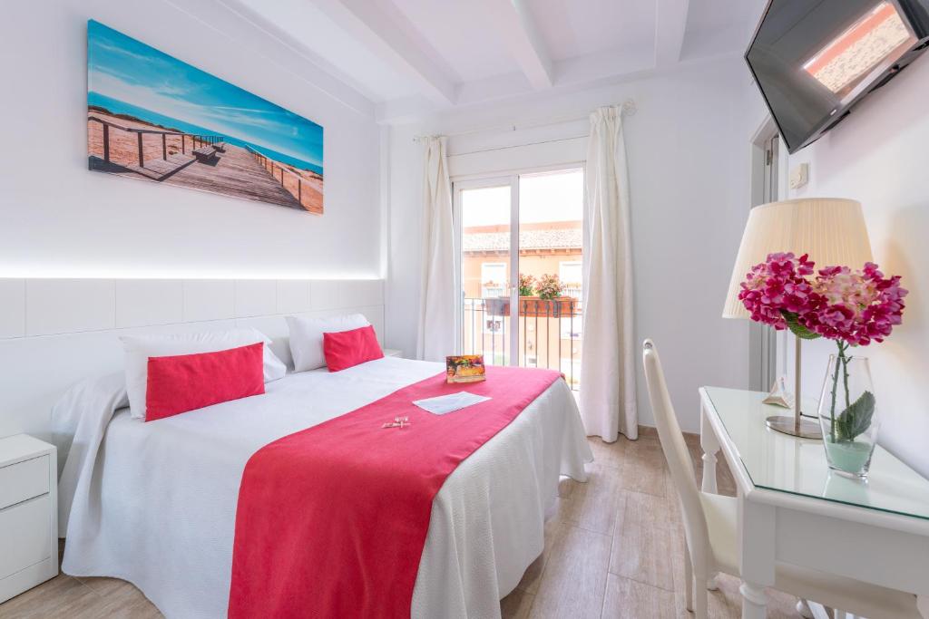 a hotel room with a bed, table, lamp and window at Romerito in Málaga